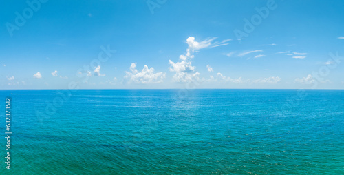 panoramic drone view of ocean with clouds in blue sky
