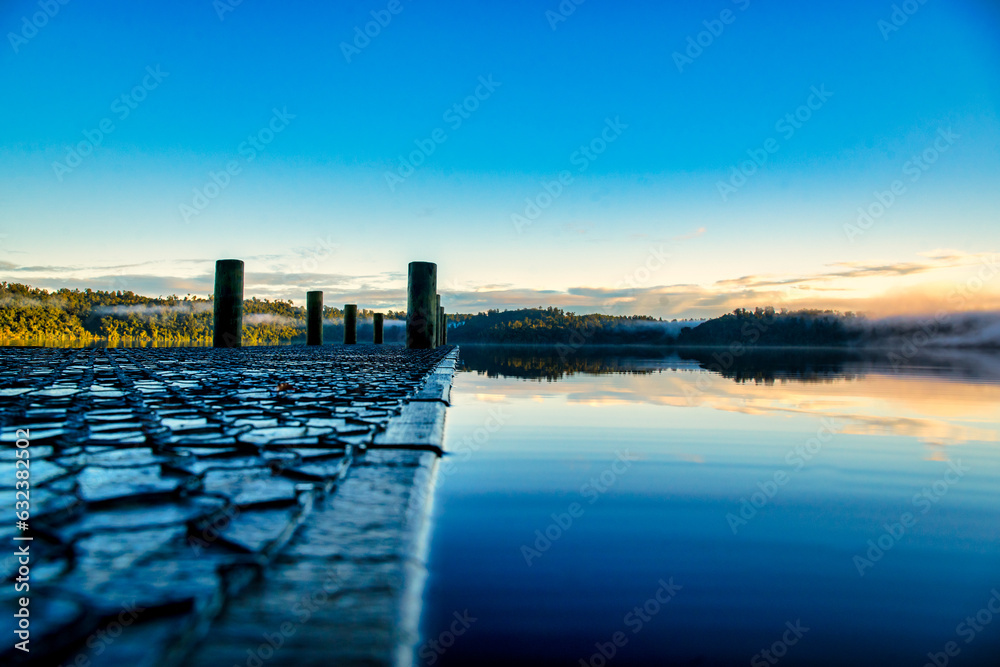 Standing on the jetty enjoying mountain and sky reflections  on the calm surface of the West Coasts Lake Ianthe