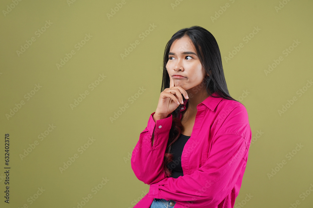 Photo of asian girl looking at copyspace touching chin thinking hand isolated on green color background Photo of asian girl looking at copyspace touching chin thinking hand isolated on green color background