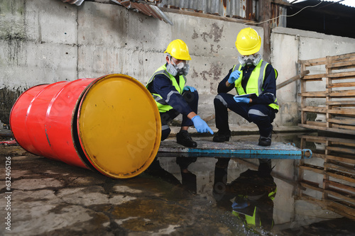 Two Officers of Environmental Engineering Wearing Protective Equipment with Gas Masks Inspected Oil Spill Contamination in Warehouse Old, Hazardous Fuel Leakage and Environmental Concept. photo