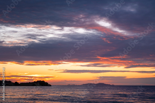 Sunset over seaand silhouette of island in Greece. Summer time and mood. Beautiful vibrant evening. Corfu island.