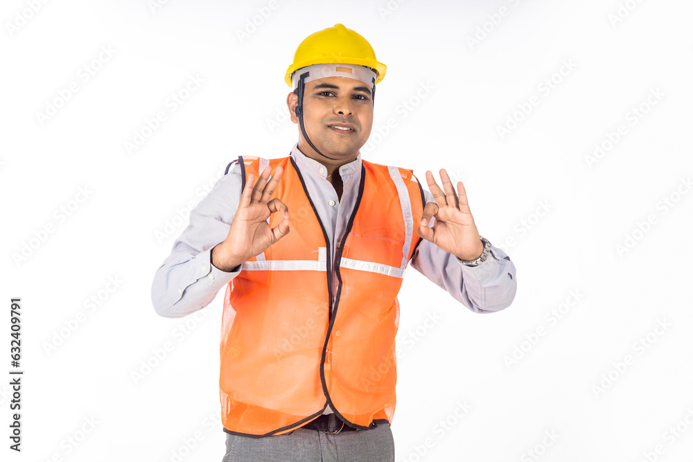 Confident engineer in uniform wearing hard hat and standing on white background.
