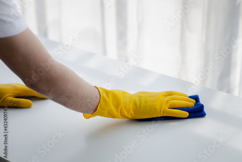 Person cleaning the room, cleaning staff is using cloth and spraying disinfectant to wipe the desk in the company office room. Cleaning staff. Maintaining cleanliness in the organization.