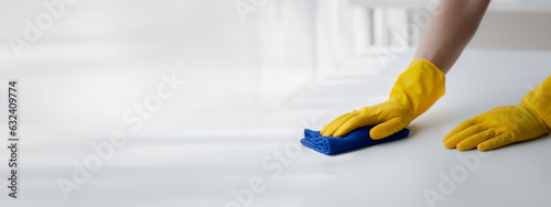 Person cleaning the room, cleaning staff is using cloth and spraying disinfectant to wipe the desk in the company office room. Cleaning staff. Maintaining cleanliness in the organization. photo