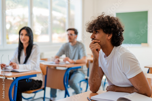 In the classroom group of college students are listening to a lecturer and involved in the discussion.