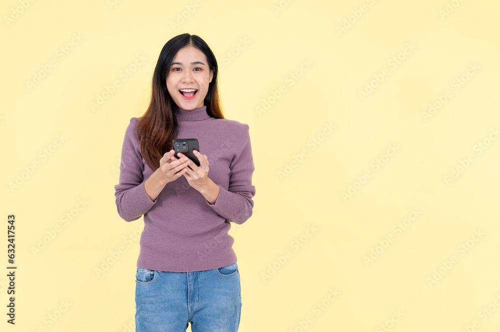 A cheerful Asian woman is holding her smartphone and smiling at the camera A cheerful Asian woman is holding her smartphone and smiling at the camera