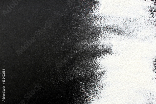 On a black background lies white wheat flour scattered with a place for text.