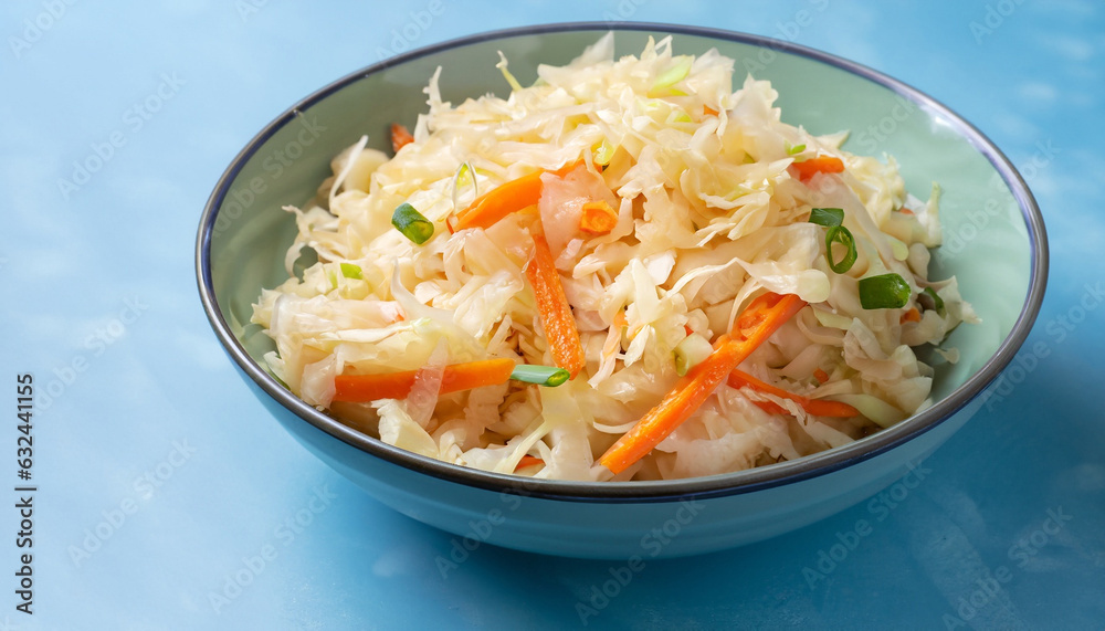 Homemade Sauerkraut with carrots and green onions in a bowl on a light blue background, Fermented food Homemade Sauerkraut with carrots and green onions in a bowl on a light blue background, Fermented food