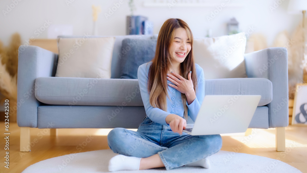 Young asian woman working on her laptop at home, grinning. attractive Asian woman utilizing computer for online schooling, video calling, and conference calls Young asian woman working on her laptop at home, grinning. attractive Asian woman utilizing computer for online schooling, video calling, and conference calls