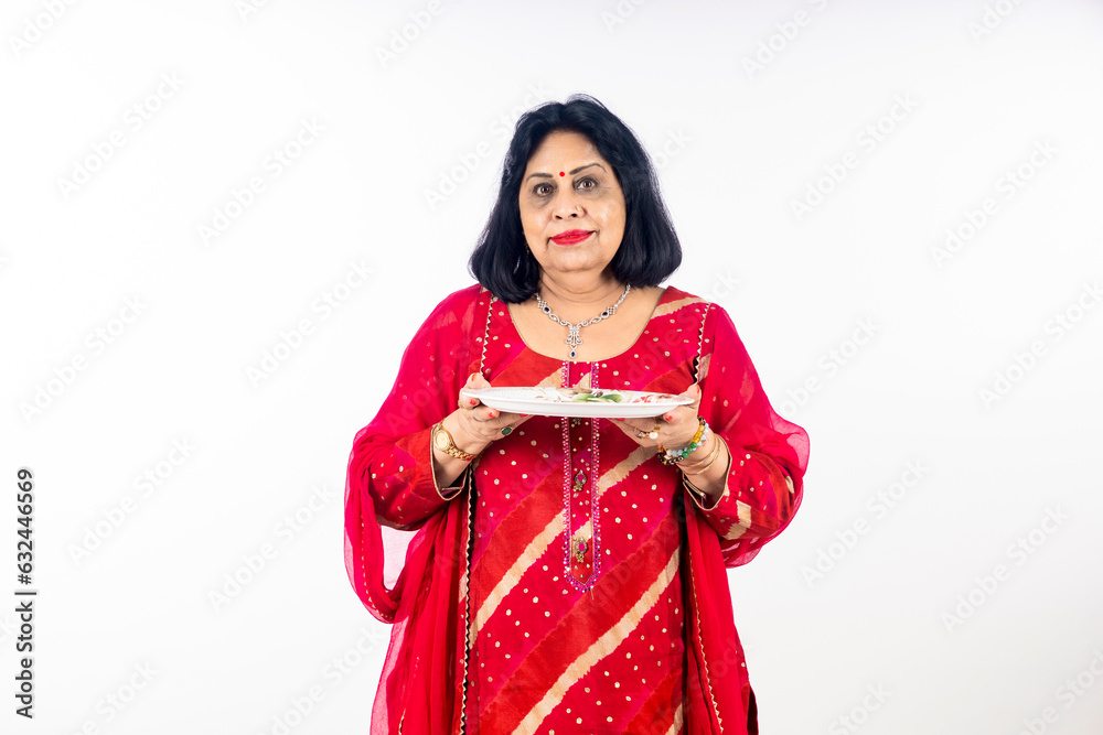 Indian woman holding pooja thali in hand on white background.