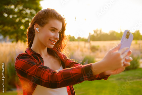 Excited young girl taking a selfie while standing in the field.