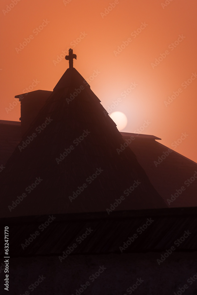 Dawn and rising sun behind the medieval church roof in Bohinj municipality, Slovenia