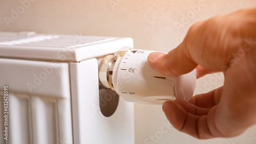 Man hand regulates temperature on light radiator attached to wall of apartment. Concept of new technologies and comfortable conditions in warmth closeup, sunlight