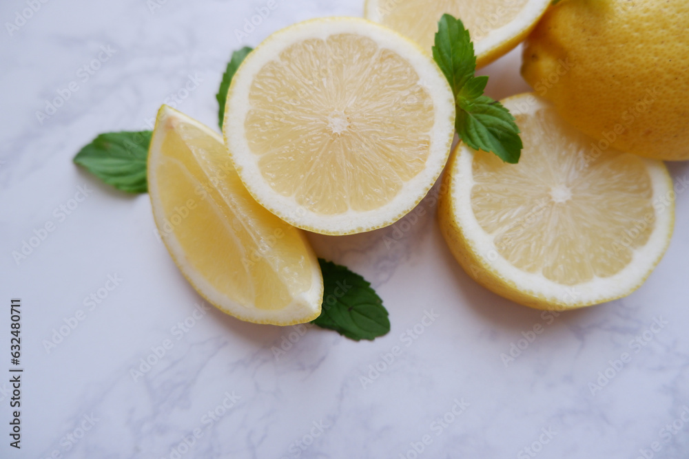 Fresh lemons and green mint composition on white marble background. Fresh tropical fruits. Slice lemon fruits. Fresh lemons and green mint composition on white marble background. Fresh tropical fruits. Slice lemon fruits.