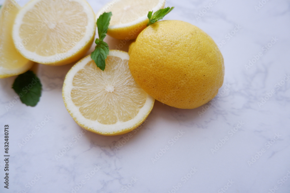 Fresh lemons and green mint composition on white marble background. Fresh tropical fruits. Slice lemon fruits. Fresh lemons and green mint composition on white marble background. Fresh tropical fruits. Slice lemon fruits.