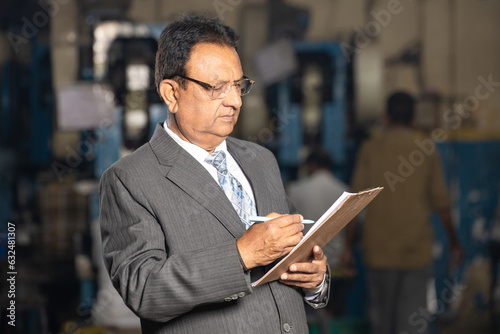Indian businessman writing some detain at factory.