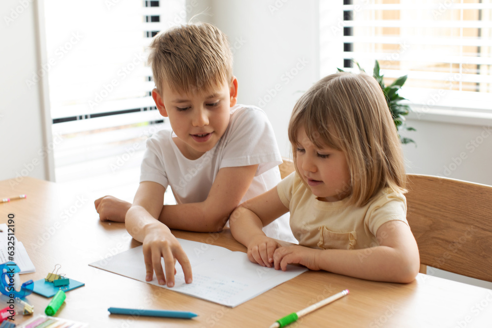 The older brother teaches the younger sister to read letters. Brother and sister, home schooling. The older brother teaches the younger sister to read letters. Brother and sister, home schooling.