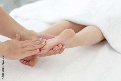 Doctor or a nurse massages the legs of a small child with her hands. Close-up of baby's foot