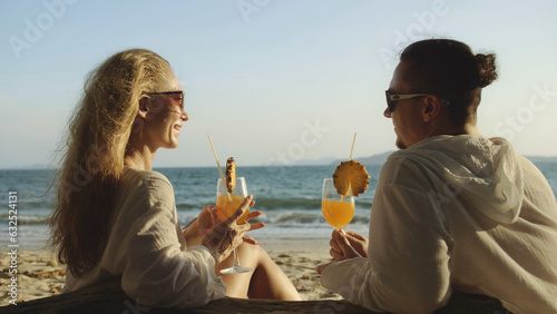 Carefree loving couple in white dress, sunglasses, relax and drinking cocktail Pina Colada, pineapple slice. Concept sea beach resting tropical tourism summer holidays wedding love family vacations