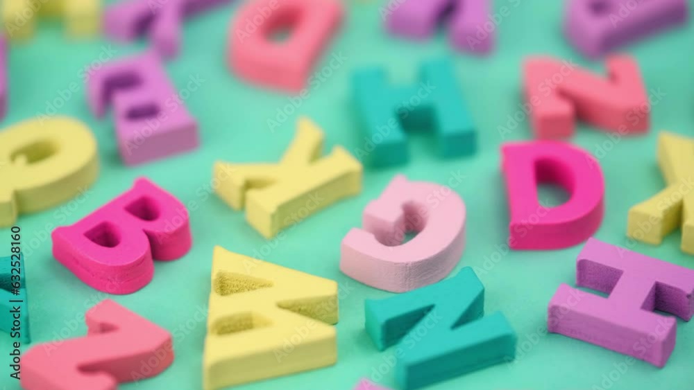 closeup wooden colorful letters of the ABC alphabet rotate on a turquoise background. back to school. concept of learning and gaining knowledge. latin alphabet. macro. closeup wooden colorful letters of the ABC alphabet rotate on a turquoise background. back to school. concept of learning and gaining knowledge. latin alphabet. macro.