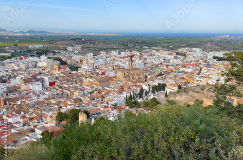 Buildings, houses and streets in city, aerial view. View of rooftops and streets of city of Sagunto in Spain. Town against backdrop of mountains. Roofs of houses and roofs from side of Sagunto Castle.