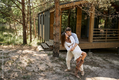 man hugging woman near vacation house, in forest, summer and romance, happiness and laughter