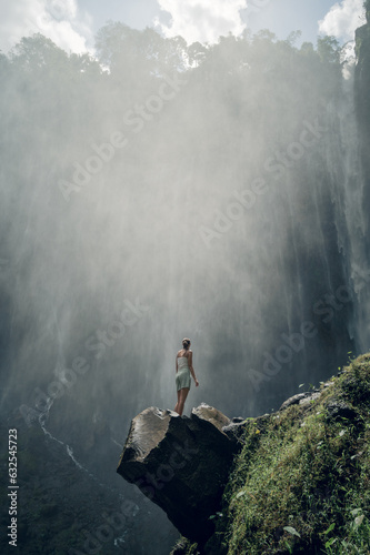A woman looking at the Tumpak Sewu waterfall in Java, Indonesia. © Arthur