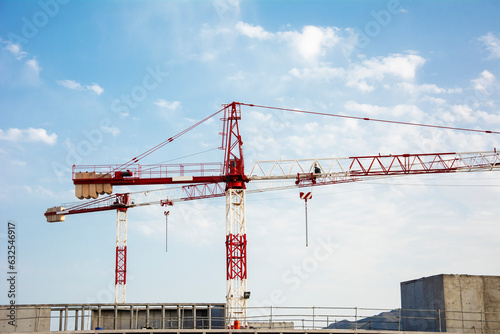 Building under construction with large tonnage cranes with the blue sky background