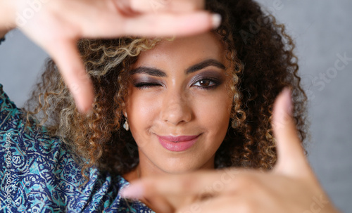 Beautiful black woman portrait. She put her hand around the frame as if she were photographing a beauty fashion style curly hair with white locks eyes look into the camera