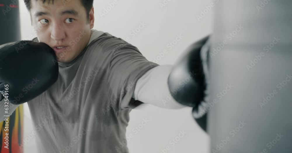 Slow motion of professional Asian fighter hitting leather punching bag indoors in gym. Fitness activity for young people and healthy lifestyle concept. Slow motion of professional Asian fighter hitting leather punching bag indoors in gym. Fitness activity for young people and healthy lifestyle concept.