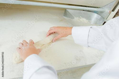 Hands shaping dough into baguette shape
