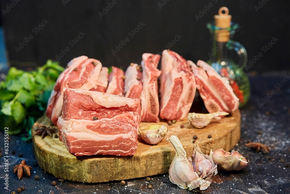 A piece of raw meat and spices lie on a wooden cutting board. Raw food for cooking.