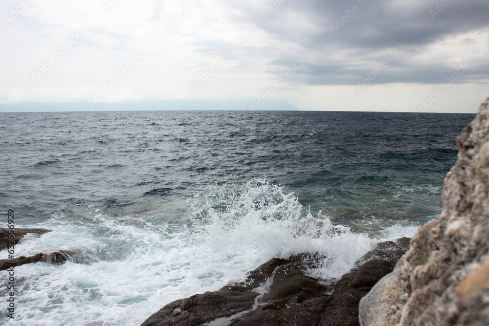Panorama of beautiful  white sea  waves and white stones. Cloudy summer time.
