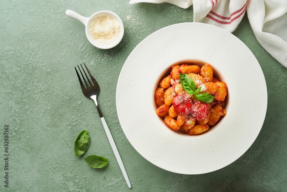 Potato gnocchi. Traditional homemade potato gnocchi with tomato sauce, basil and parmesan cheese on kitchen table on light green kitchen table background. Traditional Italian food. Top view. Potato gnocchi. Traditional homemade potato gnocchi with tomato sauce, basil and parmesan cheese on kitchen table on light green kitchen table background. Traditional Italian food. Top view.