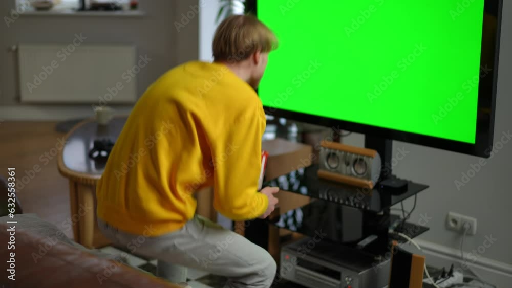 Chromakey TV screen and couch in living room with young man entering