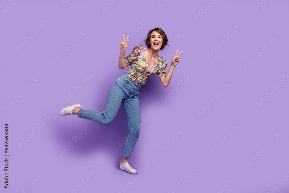 Full body photo of overjoyed pretty lady stand one leg arms fingers demonstrate v-sign empty space isolated on violet color background