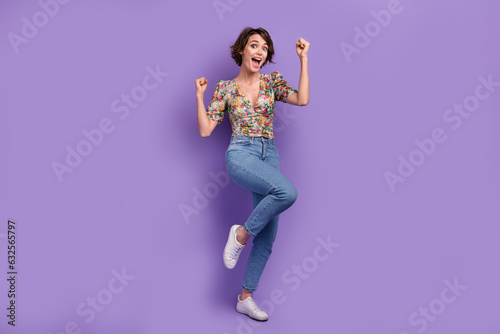 Full size photo of attractive young woman raise fist celebrate lottery wear trendy flower print clothes isolated on violet color background