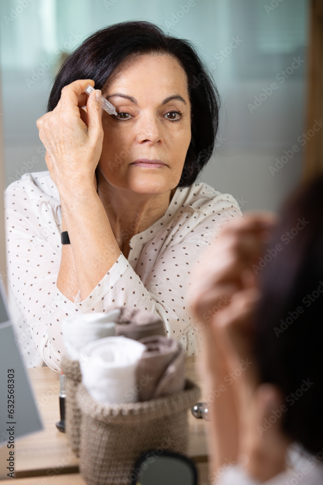 senior woman dripping some medicine with dropper on her eyes senior woman dripping some medicine with dropper on her eyes