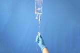 Professional opening the infusion set to delivery the drug thru intravenous infusion. Infusion set isolated in a blue background 