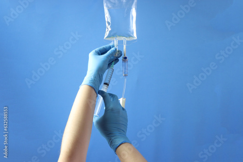 Drug bag with a infusion set connected to delivery the drug to the pacient. Professional holding the bag to infuse the drug with a syringe 