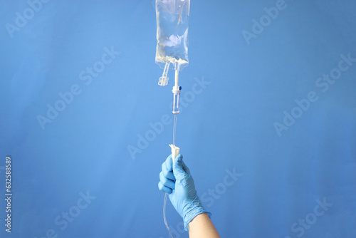 Professional opening the infusion set to delivery the drug thru intravenous infusion. Infusion set isolated in a blue background  photo