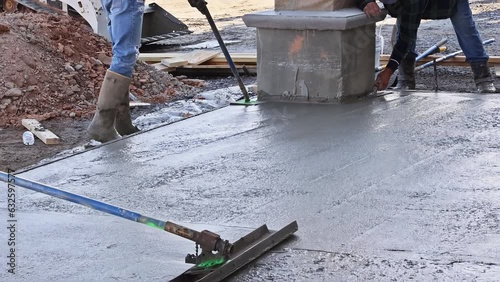 In construction site, workers are leveling concrete for driveway with readymix concrete trowel in slump concrete photo