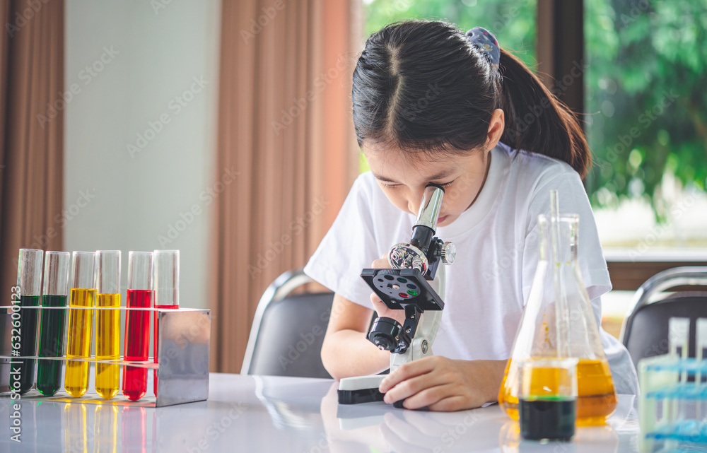 little scientist looking through a microscope and test tubes filled with chemicals for learning about science and experiments. little scientist looking through a microscope and test tubes filled with chemicals for learning about science and experiments.