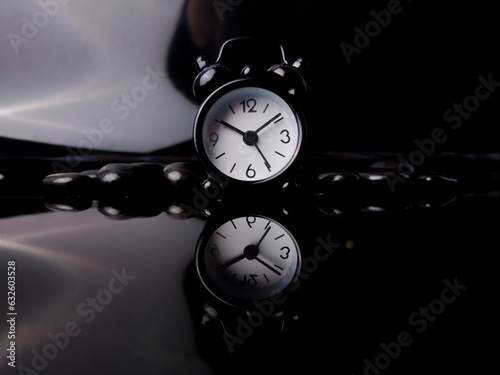Black alarm clock and black rock with reflection