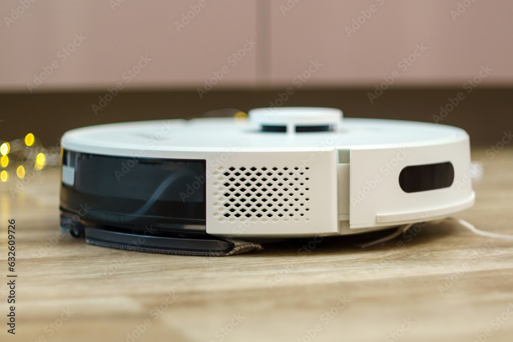 Fototapeta premium White robotic vacuum cleaner on linoleum floors smart cleaning technology. Selective focus