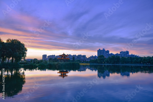 In the city park  the beautiful sunset reflects the cloudy sky and the river surface of the lotus pond