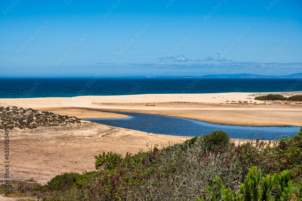 Expansive sandy Melides beach in the Alentejo region of Portugal with calm waters and a clear blue sky. Peaceful coastal scene. Expansive sandy Melides beach in the Alentejo region of Portugal with calm waters and a clear blue sky. Peaceful coastal scene.