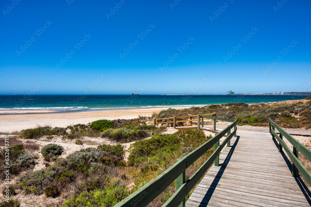 Wooden walkway leading to the sandy São Torpes beach on the Alentejo coast of Portugal under a clear blue sky. Wooden walkway leading to the sandy São Torpes beach on the Alentejo coast of Portugal under a clear blue sky.