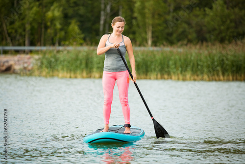 Young athletic woman paddling along the river standing on the sup board © Suzi Media 