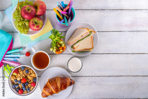 Healthy nutritious morning breakfast for school kids, with fresh fruits, vegetables, croissant, muesli, milk and sandwich. Having breakfast before school and work, copy space
